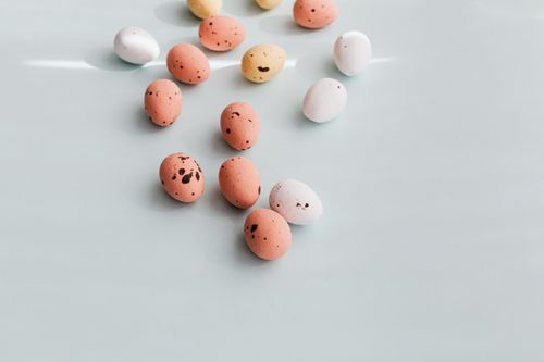 Free Easter eggs with speckled designs scattered on a pastel blue surface. Ideal for seasonal decor. Stock Photo