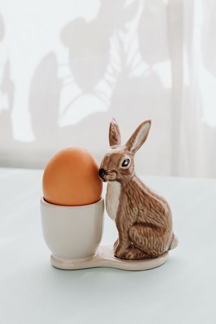 Charming ceramic bunny holding an egg, perfect for Easter decoration.
