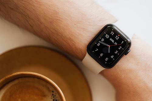 Free From above closeup of crop man hand with smart watch near cup of hot americano on white background Stock Photo