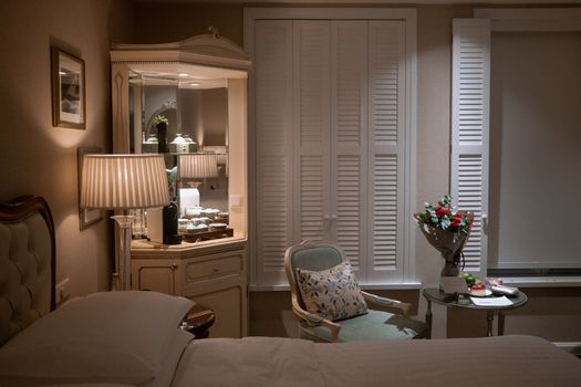 Luxurious hotel room with elegant furnishings, soft lighting, and a bouquet on a side table.