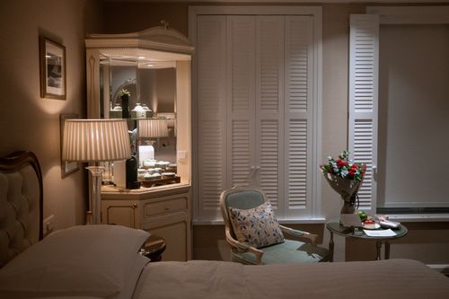 Free Luxurious hotel room with elegant furnishings, soft lighting, and a bouquet on a side table. Stock Photo