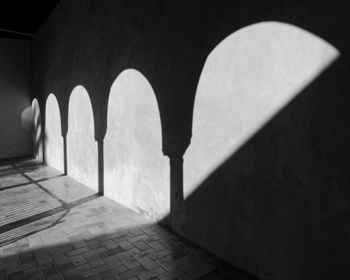 Free Black and white photo of arched shadows cast on a textured wall, creating a dramatic artistic effect. Stock Photo