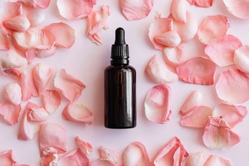 Free Set of pink petals and bottle on table Stock Photo