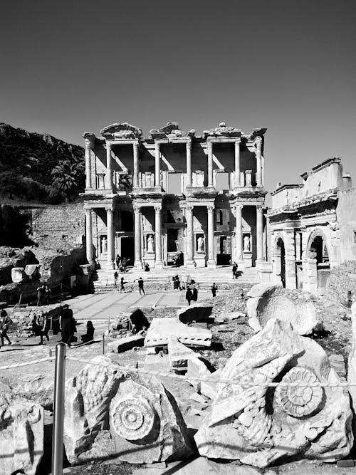 Black and white tourists walking among ancient ruins of the ancient library of Celsus in Ephesus during sightseeing