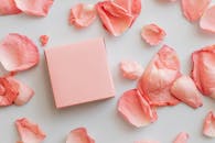 白色背景上，一个粉色礼品盒被精致的粉色玫瑰花瓣环绕，非常适合浪漫场合