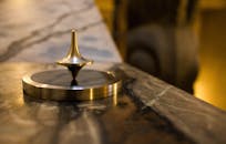 特写镜头下，室内豪华大理石表面上的金色金属陀螺正在旋转