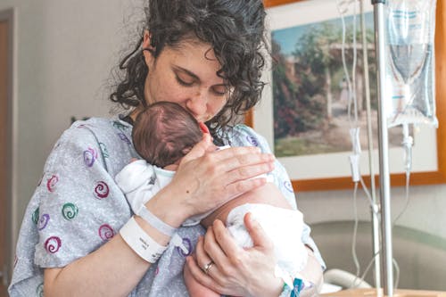 Free Photo of a Woman with Curly Hair Carrying Her Baby Stock Photo