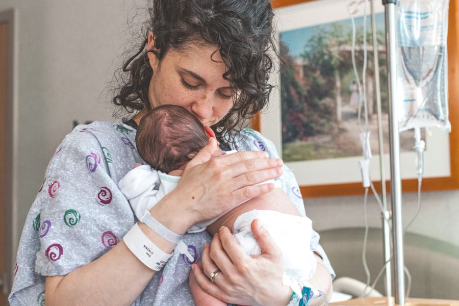 A mother gently holding her newborn baby in a hospital setting