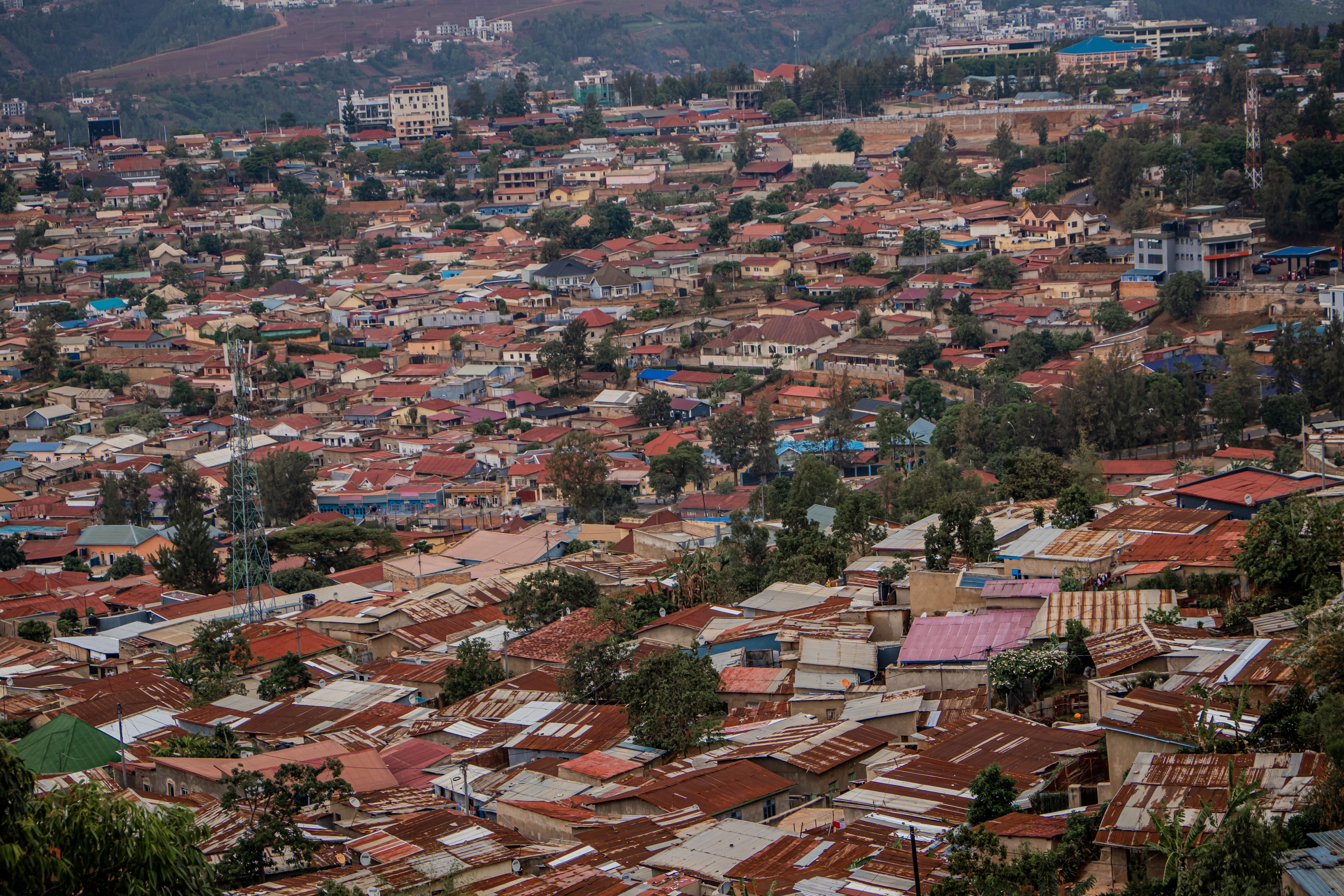 Aerial view of Kigali's urban sprawl with colorful rooftops and scenic hills.