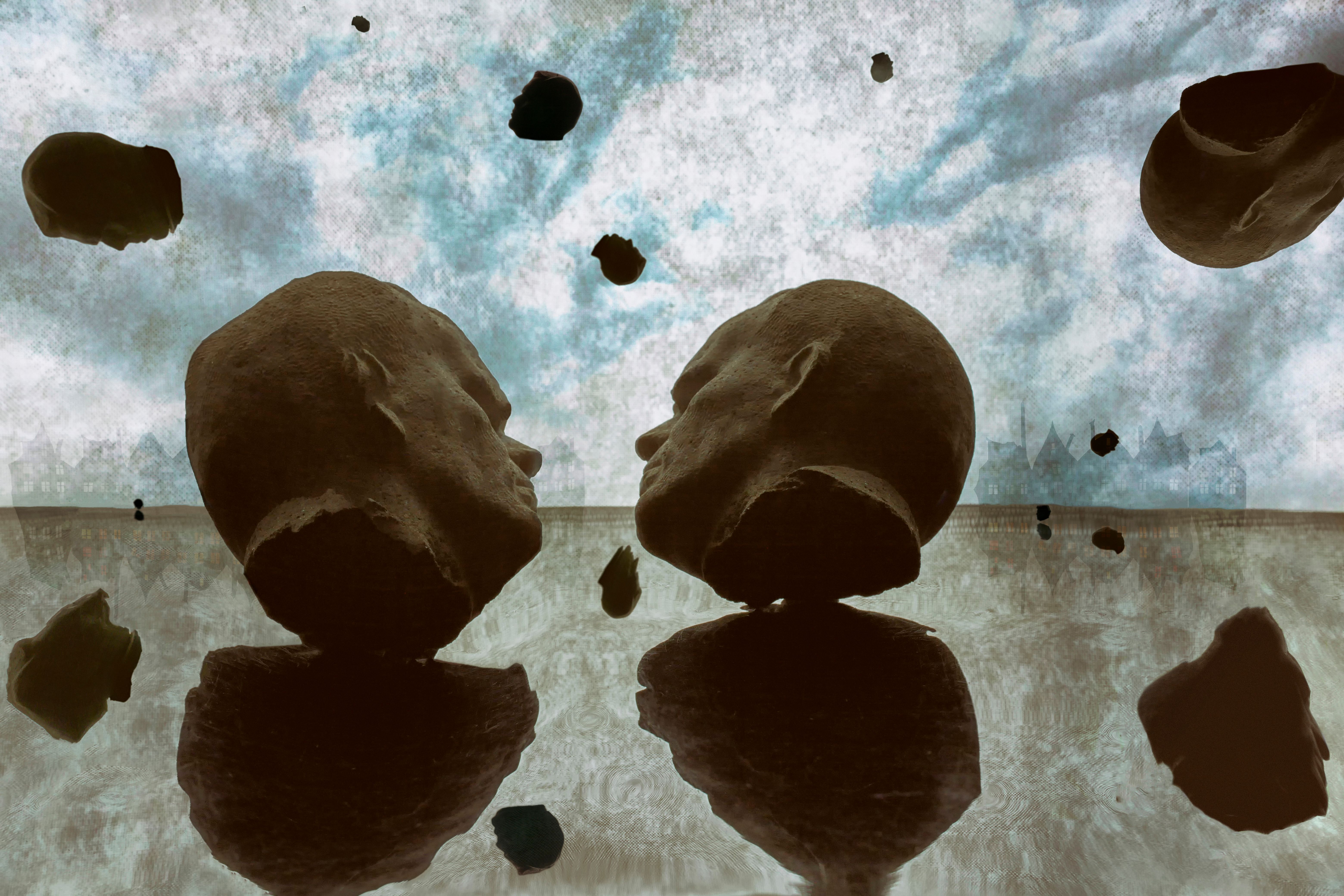 Surreal Floating Stone Heads Against Cloudy Sky · Free Stock Photo