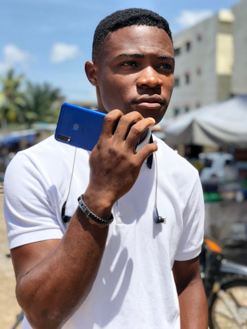 Free Portrait of a Man in a White Shirt Holding a Mobile Phone Stock Photo