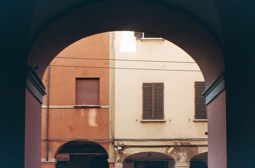 Free A view through an archway showcasing traditional buildings in Bologna, Italy. Stock Photo