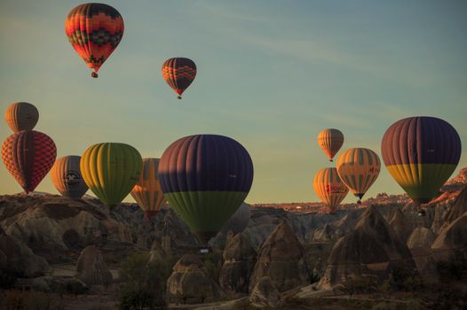 Colorful hot air balloons soaring over Cappadocia's iconic landscape at sunrise, Türkiye.