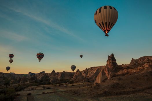 Scenic view of hot air balloons floating over Cappadocia's unique rock formations during sunrise.