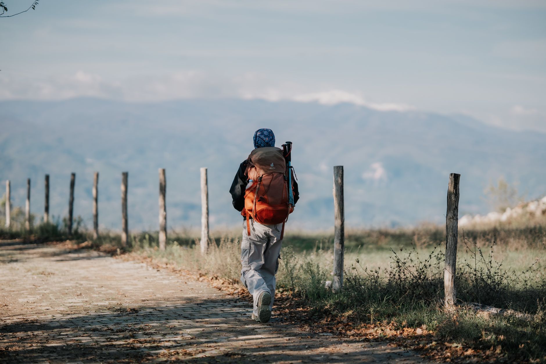 A lone backpacker walks along a rustic path with scenic mountain views, perfect for adventure travel themes.