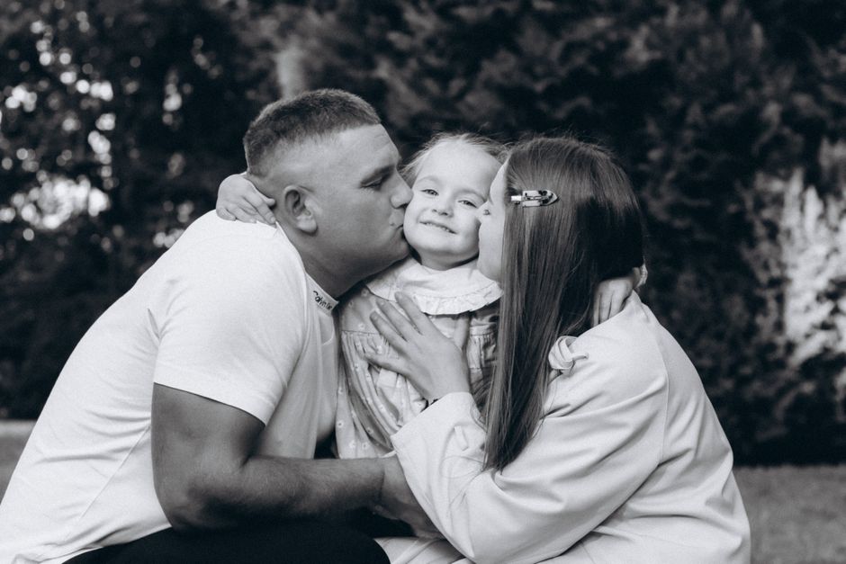 A family shares a tender moment in a garden in Wrocław, Poland, showcasing love and togetherness.