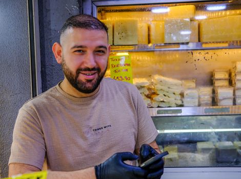 Smiling vendor in İzmir showcasing cheese in a local store.