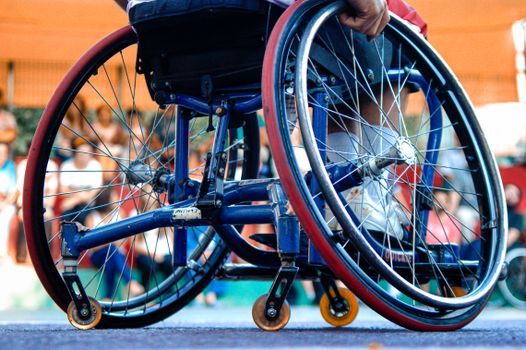 A close-up view of a blue wheelchair with a person outdoors, capturing a sense of mobility and inclusion.