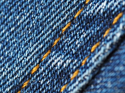 Free Detailed macro image of blue denim fabric showing yellow stitching and texture. Stock Photo