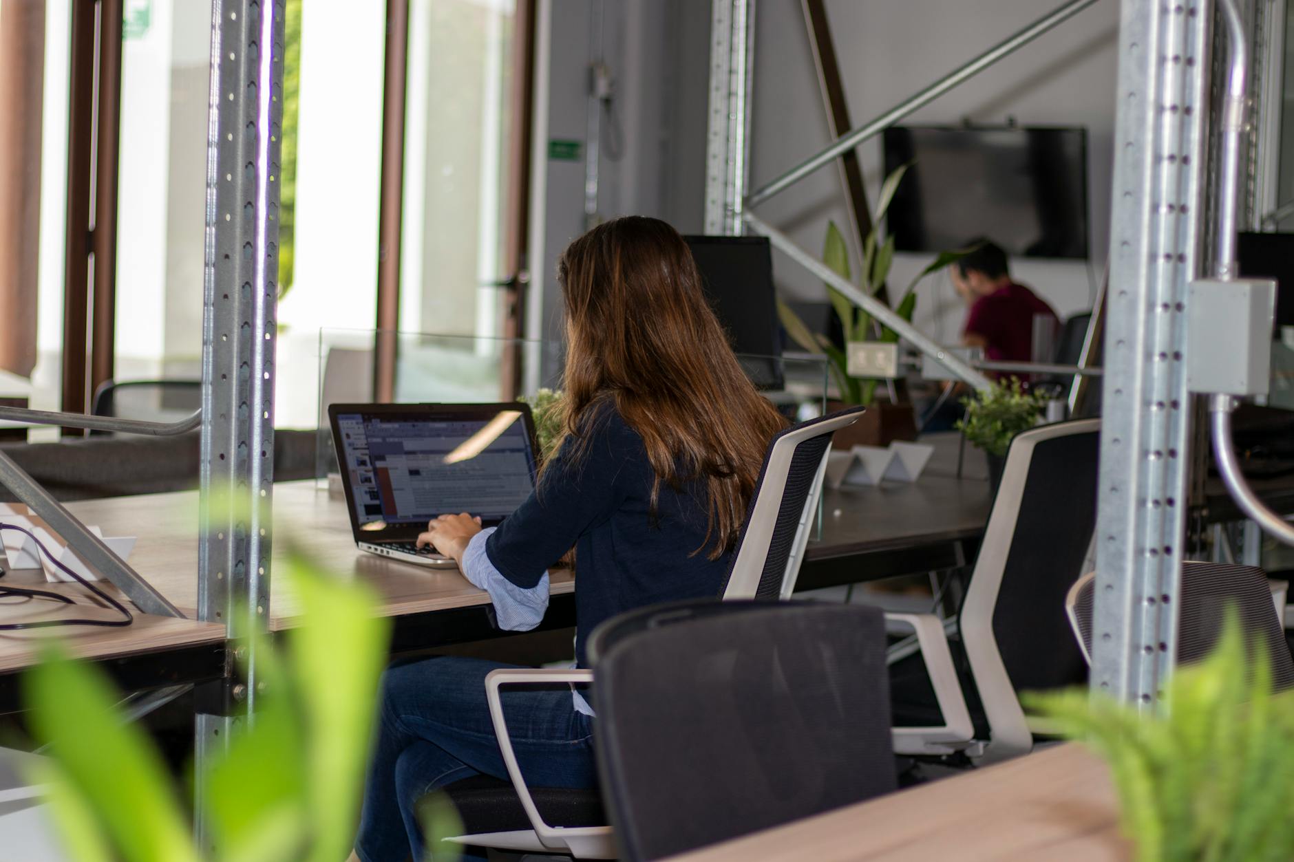 jeune femme buvant un café tout en tapant sur son ordinateur portable dans un espace de coworking lumineux
