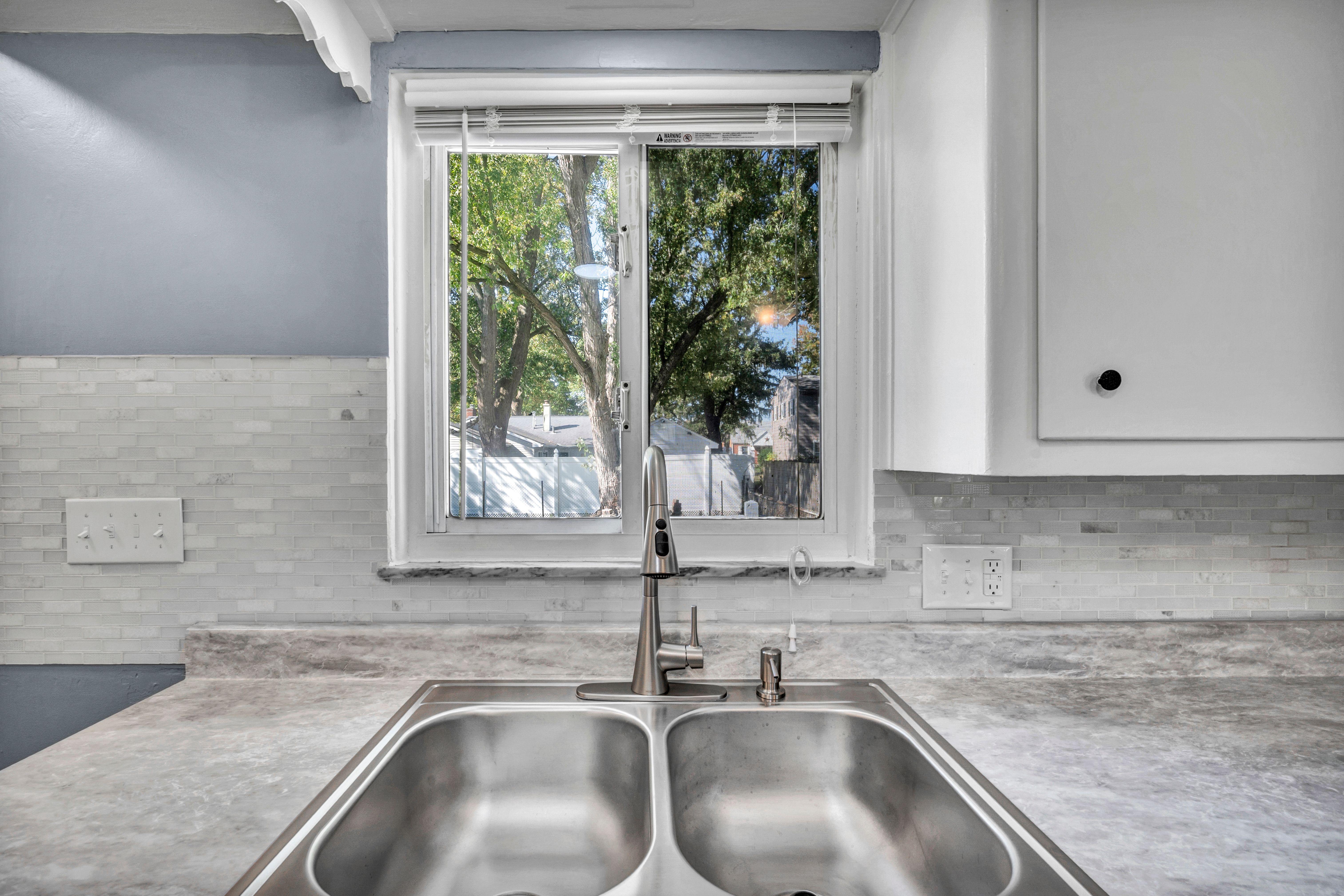 A bright kitchen interior with a modern double sink and window view.