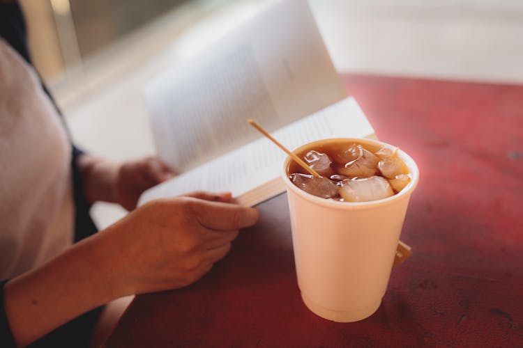 Woman Reading A Book And Drinking Iced Tea