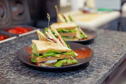 Free Tasty club sandwiches with fresh greens on a granite counter, ready to serve. Stock Photo