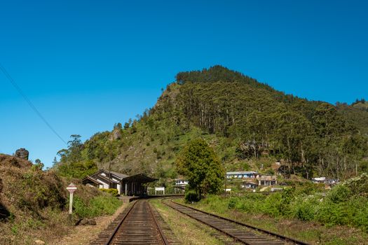Railway tracks leading through Haputale's lush landscape under a clear blue sky in Uva Province, Sri Lanka.