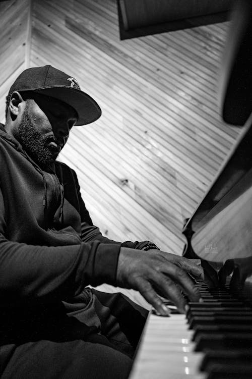 Unrecognizable black male musician playing piano in attic style room