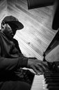 Unrecognizable black male musician playing piano in attic style room