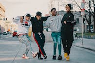 在城里开车和停车附近的柏油路上，穿着时髦服装的年轻开朗的多种族男友们单腿站立拥抱在一起