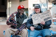 Cheerful diverse hipster friends showing inscription on cardboard piece outdoors