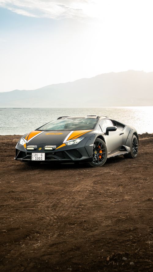 Free Sleek sports car parked by a scenic lake during a serene sunset, perfect for automotive enthusiasts. Stock Photo