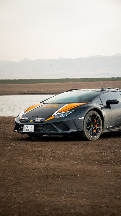 Free Dynamic shot of a sports car parked on a rural road against a serene mountain backdrop. Stock Photo