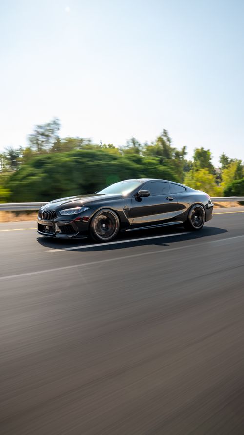 Free Dynamic shot of a black sports car speeding on an open highway under clear skies. Stock Photo