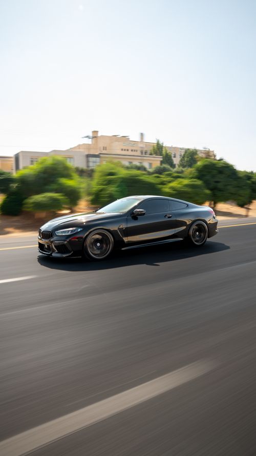 Free Dynamic shot of a sleek black sports car speeding down an open road on a sunny day. Stock Photo