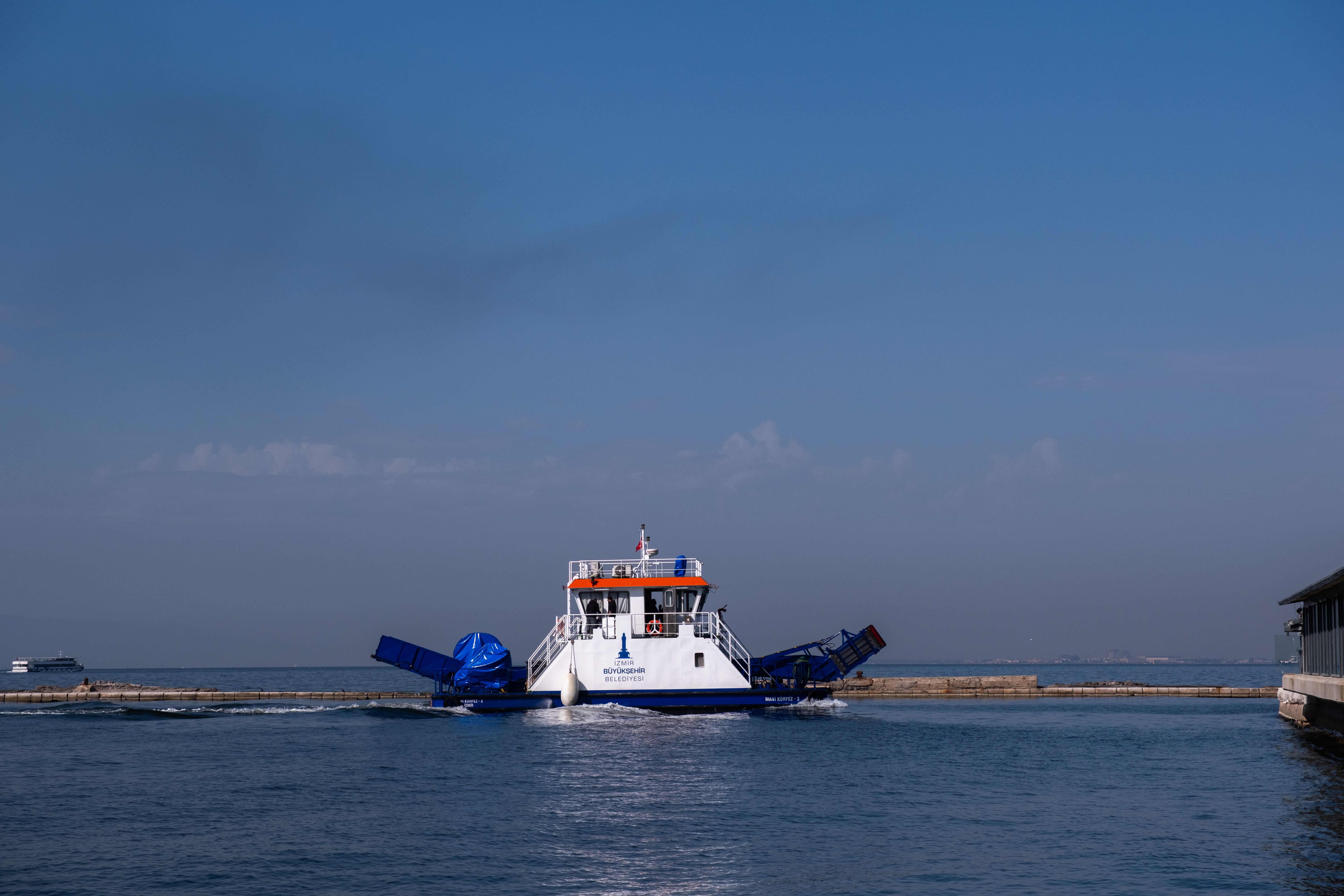 Ferry approaching a dock under a clear blue sky in Izmir, Türkiye.