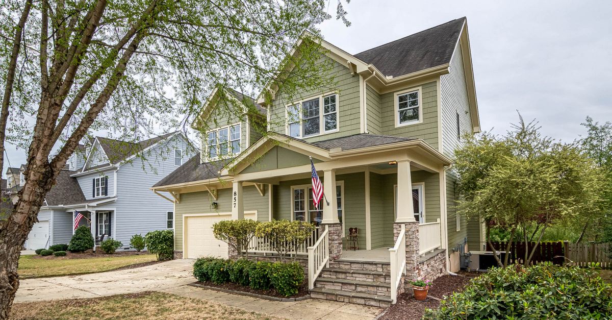 Spacious suburban house with porch, garden, and American flag, perfect for real estate listings.