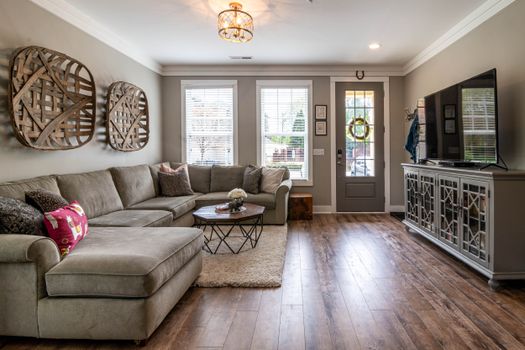 Spacious living room featuring a large sofa, wooden floor, and stylish decor.