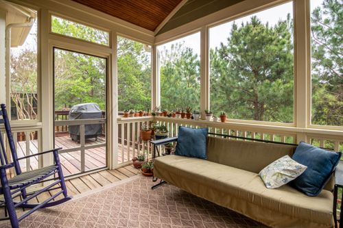 Free Relaxing screened porch with couch, plants, and outdoor greenery view. Stock Photo
