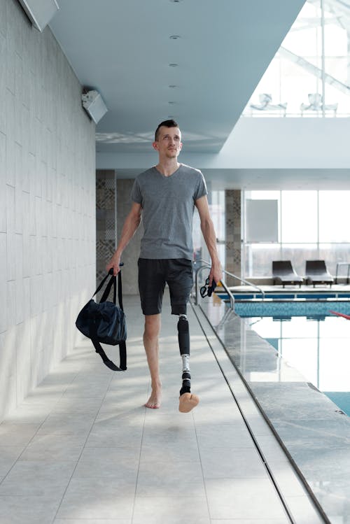 Man with Prosthetic Leg Walking by Swimming Pool