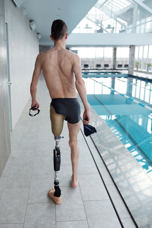 Free Man with Prosthetic Leg Walking by Swimming Pool Stock Photo