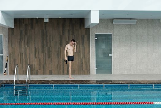Amputee athlete preparing at an indoor swimming pool, portraying determination and fitness.