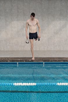 Young amputee athlete preparing to swim at an indoor pool, showcasing strength and determination.