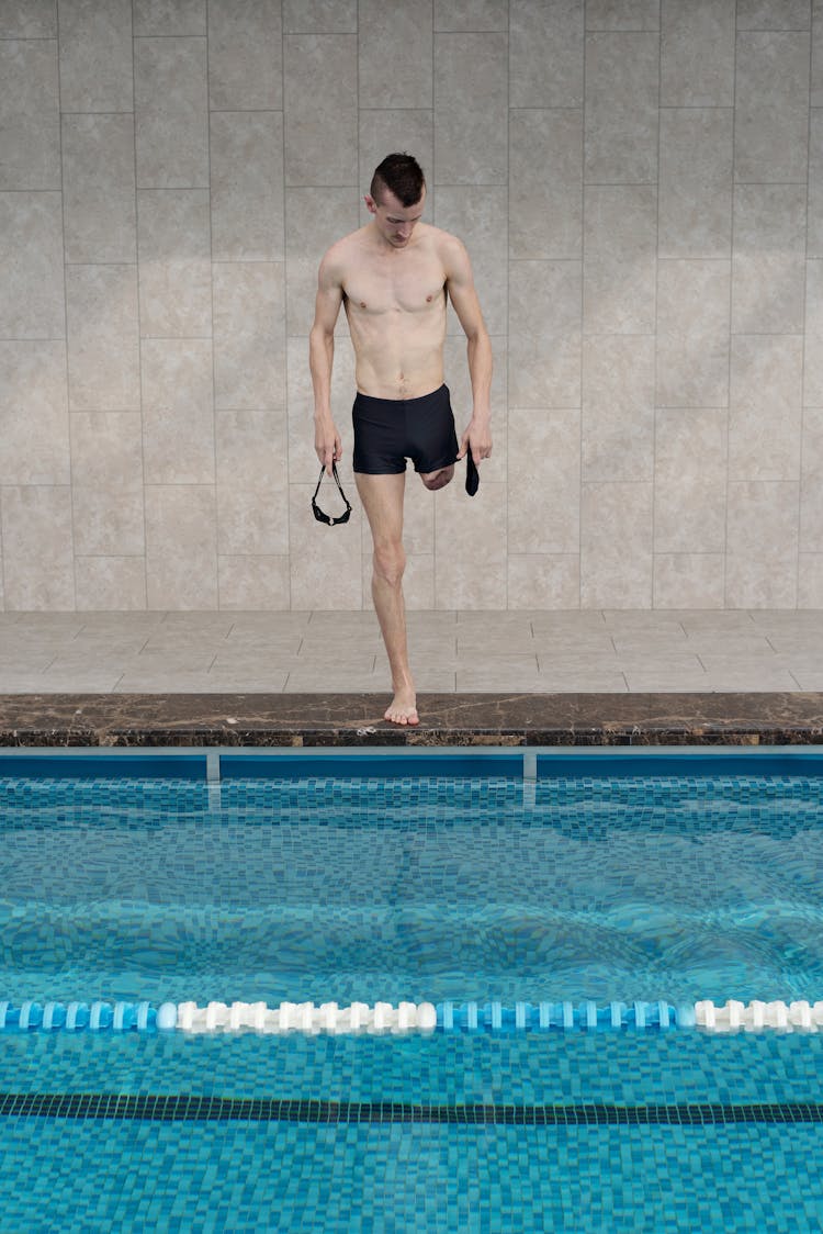 Man In Black Shorts Standing By Swimming Pool