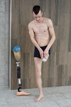 年轻的截肢男运动员在室内游泳前调整假肢