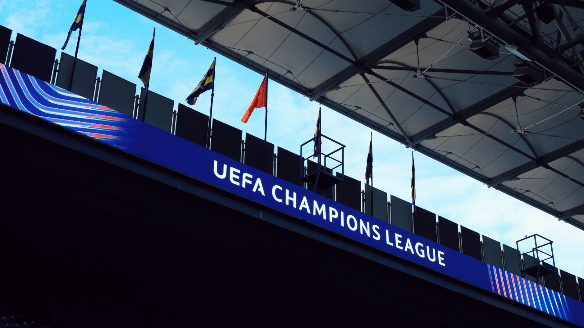 UEFA Champions League signage inside a stadium with flags and architectural details.