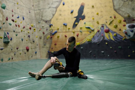 Man with a prosthetic leg preparing for indoor climbing on a colorful climbing wall.