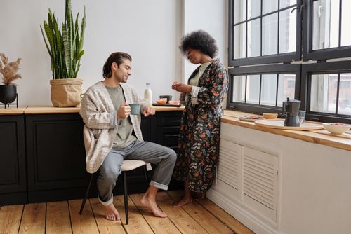 Free Couple enjoying morning coffee together in a cozy kitchen setting. Stock Photo