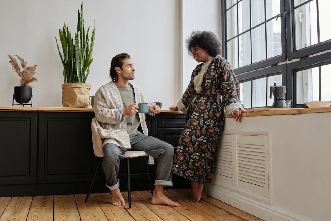 Free Man Sitting with a Mug and a Woman Standing next to him Stock Photo